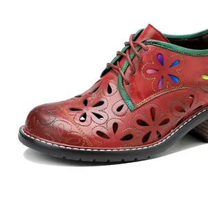 Close-up of vintage red genuine leather lace-up shoe with floral cutouts and contrast trim