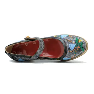 Detailansicht von Vintage Mary Jane Pumps mit farbenfroher Blumenstickerei auf grauem Stoff.