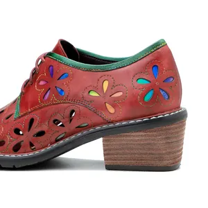 Detail view of red vintage leather shoe with colorful flower cutouts and block heel.
