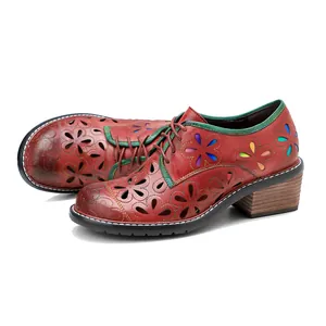 Detail view of vintage red leather shoes featuring handmade flower hollow-out patterns.