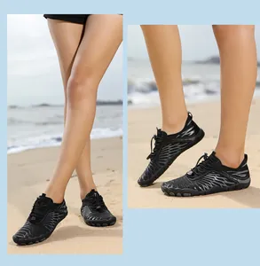 Black breathable water shoes with non-slip soles worn on a sandy beach scene