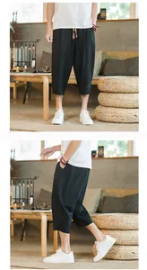 Detailed side and front view of men's black linen cropped harem pants in a zen setting