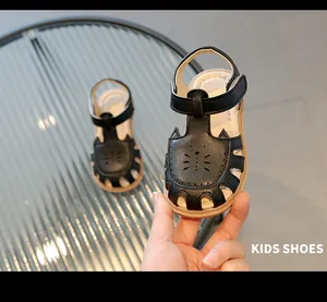 Gros plan de sandales noires pour enfants avec découpes mignonnes en forme de chat.