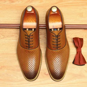 Chaussures richelieu pour hommes en cuir marron perforé respirant sur fond en bois