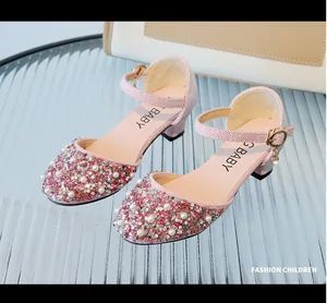 Close-up of pink glitter children's high heels with pearls and buckle strap detail.