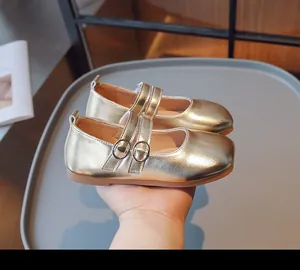 Detailansicht glänzender goldener Mädchen-Mary-Janes mit doppelten Schnallenriemen.