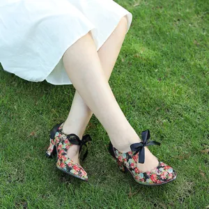 Elegant vintage floral print high heels with black bow tie shown on green grass background