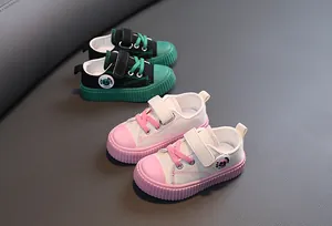 Gros plan de chaussures en toile pour enfants roses et vertes avec bandes velcro.