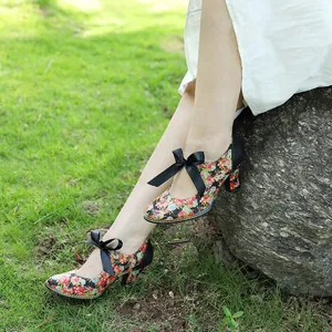 Vintage American pastoral floral high heels with black ribbon bows worn in a nature setting
