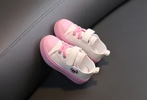 Détail de baskets en toile pour enfants roses et blanches avec scratch et semelle en caoutchouc.