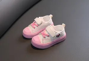 Paire de baskets basses en toile pour enfants en rose et blanc avec fermeture velcro.