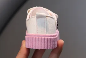 Vue détaillée de l'arrière d'une chaussure en toile blanche pour enfant avec semelle rose.