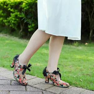 Close-up of vintage floral high heels with elegant black ribbon bow in garden setting
