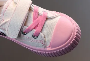 Gros plan sur l'embout en caoutchouc rose des baskets en toile crème pour enfants avec velcro
