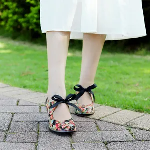 Detail of vintage floral high heels featuring elegant black bow straps in a garden.