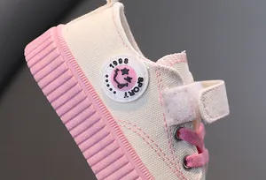 Gros plan détaillé des baskets en toile pour enfants roses et blanches avec écusson sport
