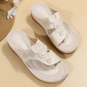 Detailed view of women's beige wedge thong sandals with decorative laser-cut patterns