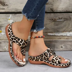 Close-up detail of leopard print wedge thong sandals worn on model feet in rustic setting
