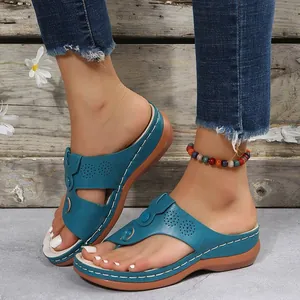 Close-up of blue wedge thong sandals with white stitching details worn by a model