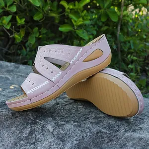 Détail de sandales compensées roses avec broderies florales et coutures blanches