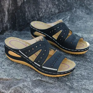 Vue latérale de sandales compensées noires avec broderie florale et coutures blanches