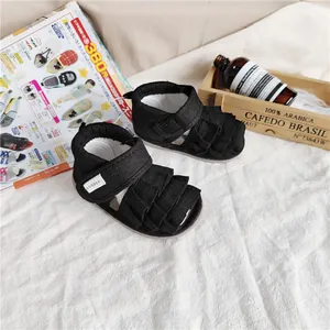 Detailaufnahme von schwarzen Baby-Mädchen-Sandalen mit Rüschen und CONOCO-Logo.