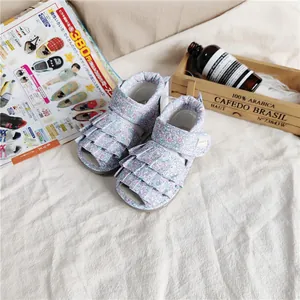 Nahaufnahme der Conoco Baby-Sandalen mit Blumenmuster und Rüschen in gemütlichem Ambiente