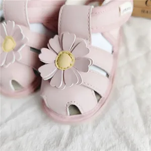 Nahaufnahme rosa Baby Mädchen Sandalen mit dekorativen Gänseblümchen Blumen Applikationen