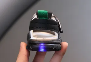 Detailansicht einer Kleinkindsandale mit einem hell blinkenden blauen LED-Licht an der Ferse