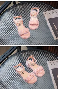 Gros plan détaillé des sandales roses pour filles avec perles et volants satin.