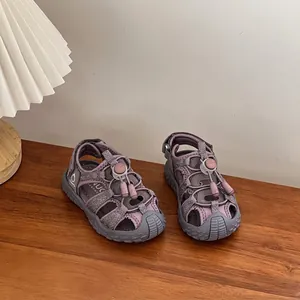 Close-up view of children's purple sports sandals on a wooden table with a soft lamp.