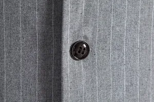 Close-up detail showing the resin button and gray pinstripe fabric of a men's retro vest.