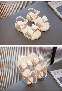 Detailansicht der beigefarbenen Mädchensandalen mit eleganter weißer Schleife und Perlen