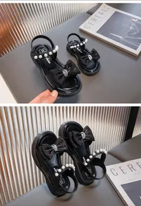 Detailansicht schwarzer Mädchen Sandalen mit Perlenriemen und eleganter Schleife Deko