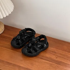 Close-up of black children's sports sandals with hollow-out design on wooden table