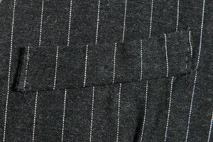 Detailed macro view of black pinstripe fabric texture and pocket stitching on men's vest