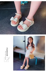 Detailansicht von weißen Mädchen-Prinzessin-Sandalen mit Perlenriemen und Schleifen