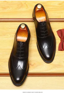 Nahaufnahme von schwarzen Leder-Oxfords für Herren mit Holzschuhspannern und Fliege.