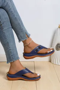 Dettaglio dei sandali con zeppa blu traforati e suola spessa indossati dal modello