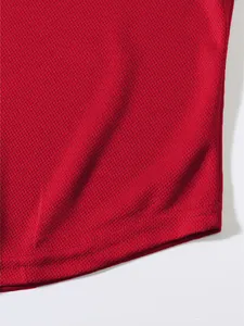 Dettaglio macro del tessuto a rete traspirante rosso sulla canotta sportiva da uomo