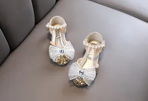 Nahaufnahme goldener Prinzessinnen-Sandalen für Mädchen mit Spitzenschleife
