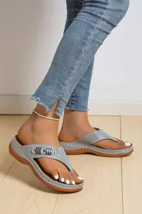 Vista dettagliata di sandali infradito con zeppa grigi da donna con design traforato.