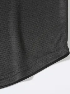 Dettaglio ravvicinato del tessuto mesh nero traspirante e dell'orlo curvo della canotta.