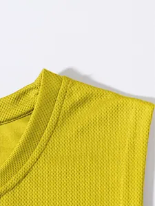 Primo piano del tessuto a rete traspirante giallo su canotta sportiva da uomo con scollo a giro.
