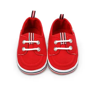 Primer plano de zapatos de lona roja para bebé con cordones blancos y detalles a rayas