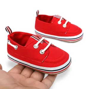 Primer plano detallado de zapatos de lona rojos para bebés sostenidos en la mano para ver la talla