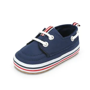 Primer plano de zapatillas de lona azul marino para bebé con suela de rayas y cordones blancos.