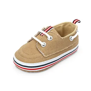 Detail van bruine canvas babyschoentjes met rood-wit gestreepte zool voor baby's 0-1 jaar.