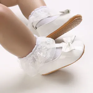 Detailansicht weißer Baby-Lauflernschuhe mit eleganten Spitzensöckchen und Schleifen