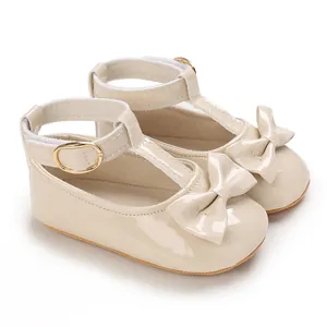 Detailansicht der beigen Babyschuhe mit glänzendem Finish und süßer Schleife